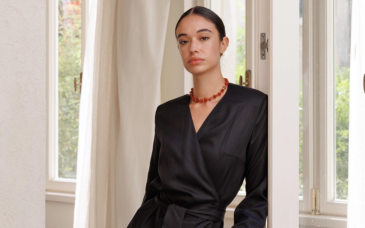 Model wearing the Leah Dress in Black by a window